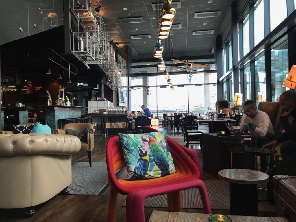 Modern ljus hotellobby, man med dator i förgrunden.