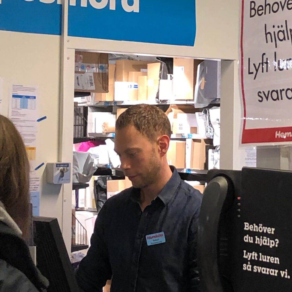 Paketutlämning i butik. En man expedierar. Många paket i bakgrunden. Många av dem är med stor sannolikhet från Kina.