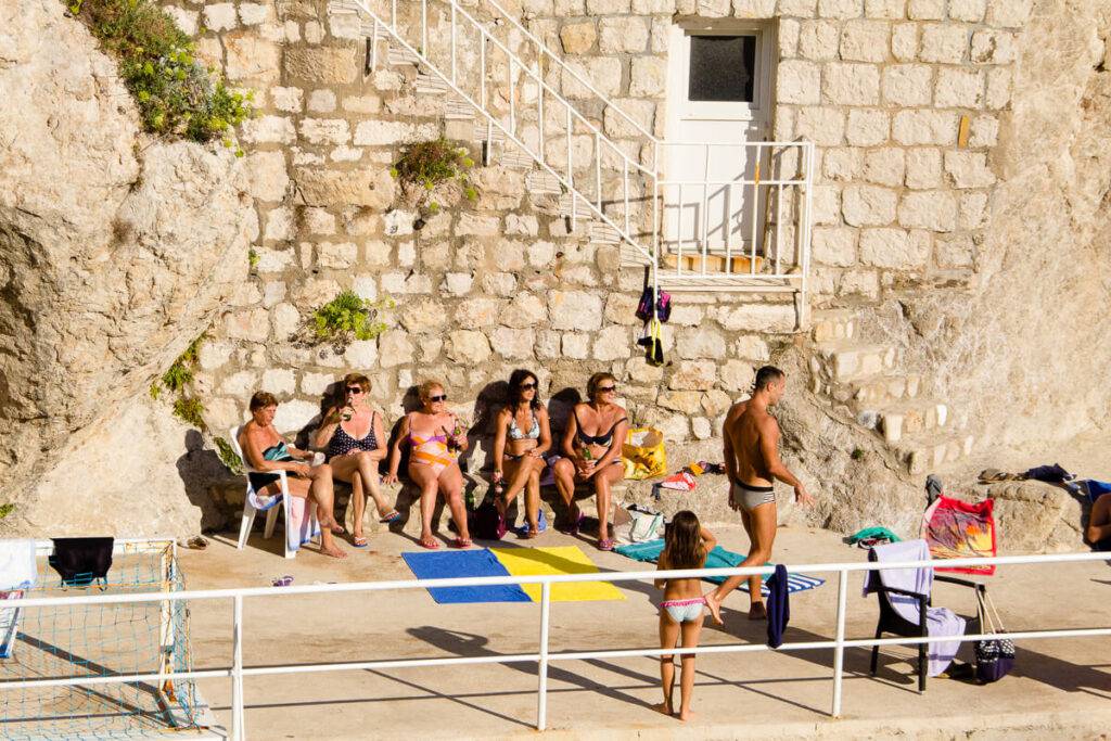 Kvinnor solar vid stranden Šulići i Dubrovnik.