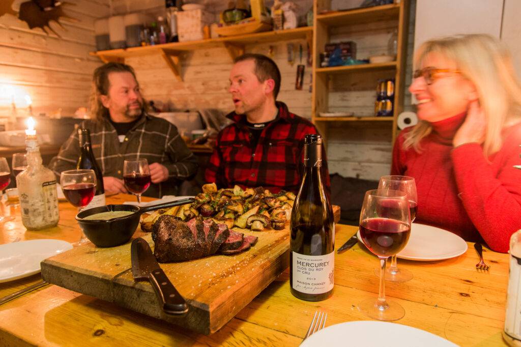 Jappe med flera runt middagsbordet. Helstekt älgentrecote och ugnsbakad potatis serveras.
