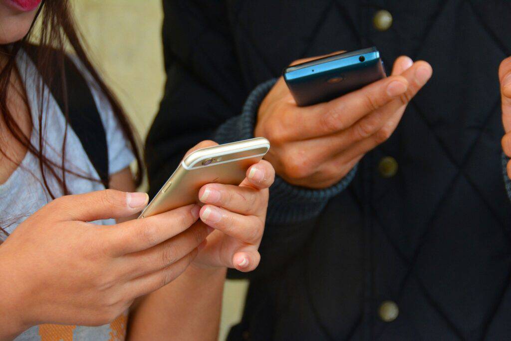 Två personer kollar i sina mobiler
