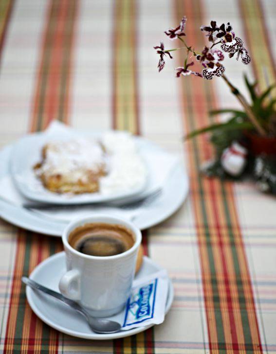 Espressokopp, bakelse och en liten orkide