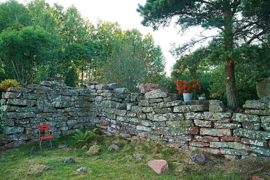 En lagård som aldrig blev klar förvandlad till klassisk trädgårdsruin. På muren nemesia och boliviafuchsia i krukor
